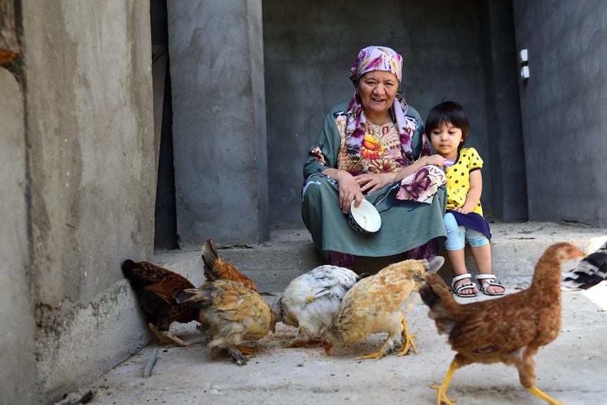 Matluba Samarova with her granddaughter Ma’rifat Sadriddin feeding the chicken.