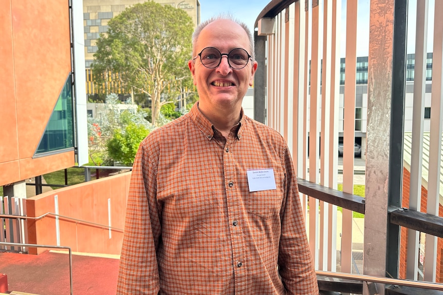 A man in glasses smiles at the camera.