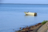 A small fishing dinghy moored off the coast in calm waters.