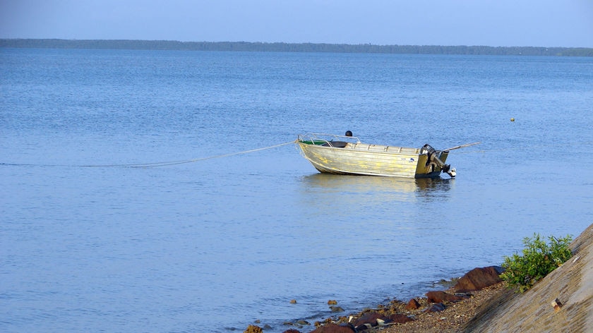 A small fishing dinghy moored off the coast in calm waters.