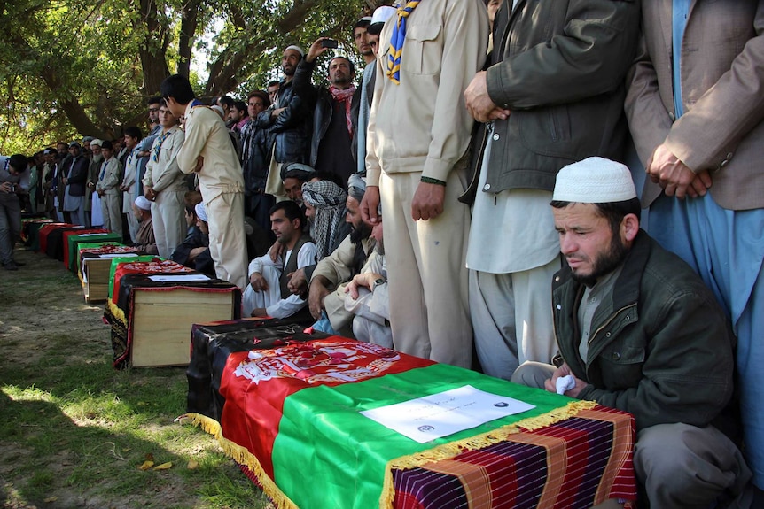 Afghan relatives sit alongside the coffins of schoolgirls killed in a stampede following an earthquake