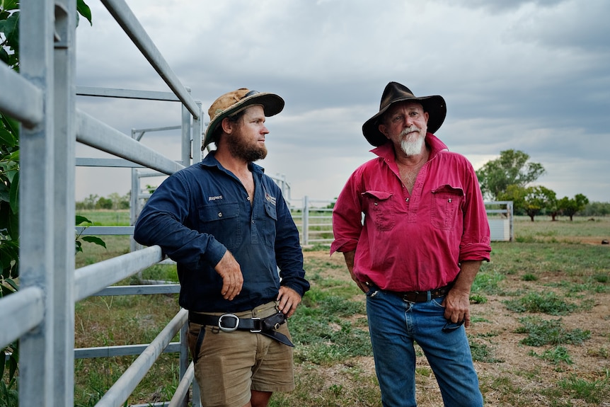 Two farmers standing in a paddock.