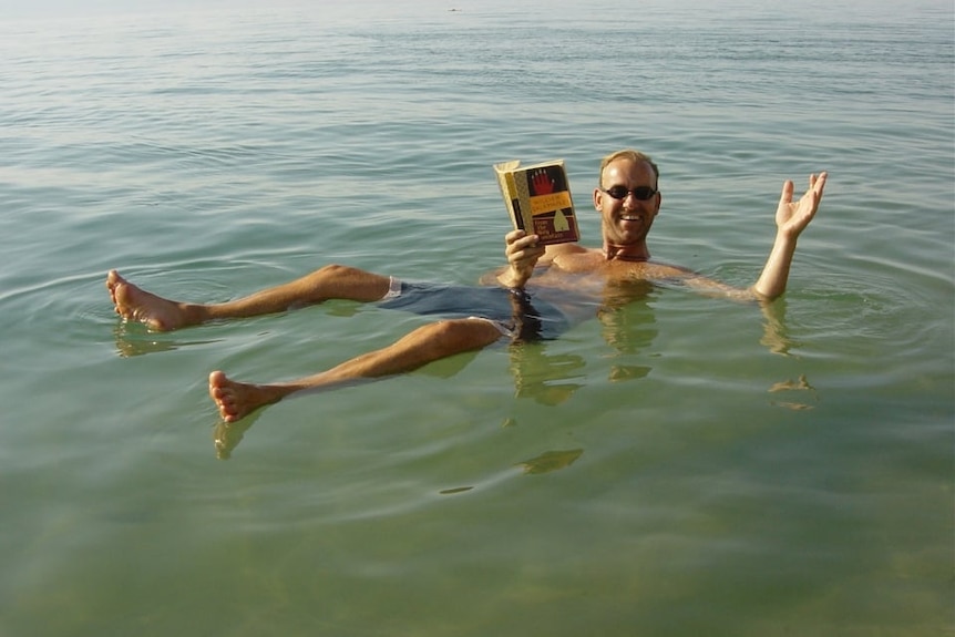 Mark Havre floating in the water whole reading a book