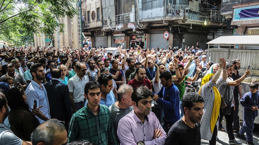 Large group of protesters chant and raise their arms in the air