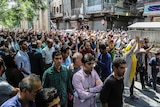 Large group of protesters chant and raise their arms in the air