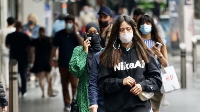 Three women wearing facemasks can be seen walking in Melbourne's CBD.