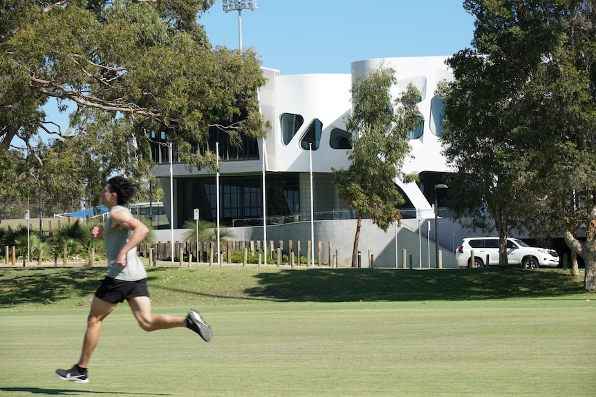 A runner runs past a modern building.