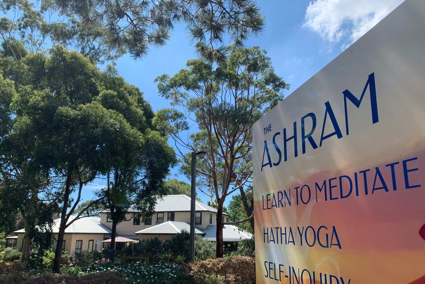 A large double-storey weatherboard building can be seen behind a sign for The Ashram.