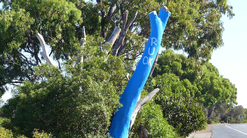 A blue tree in the centre of a group of trees