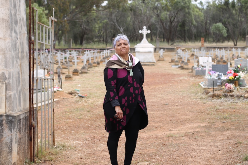 Woman standing at gates to cemetery