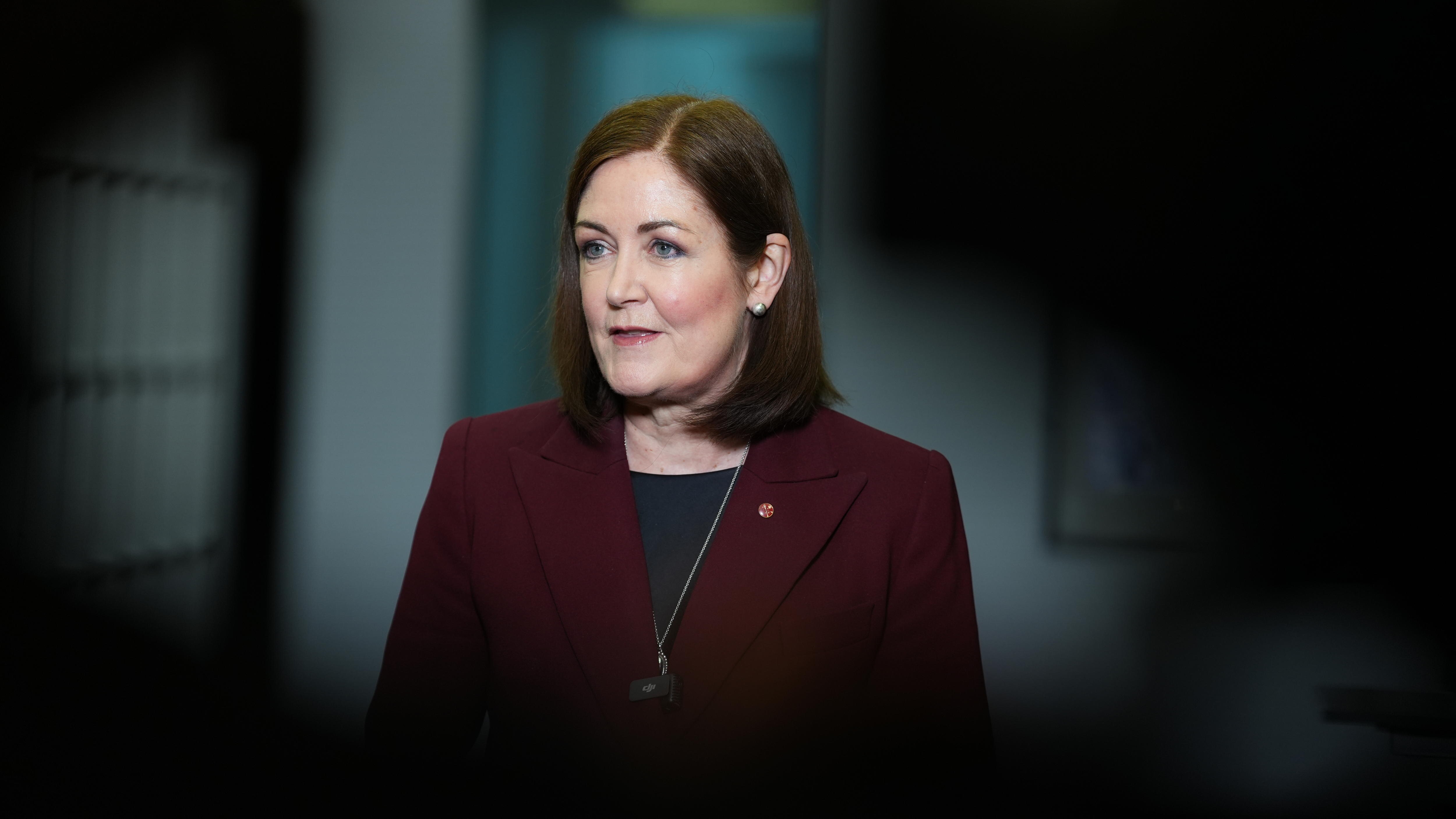 Senator Sarah Henderson speaking at press conference, looking through gap in media scrum.