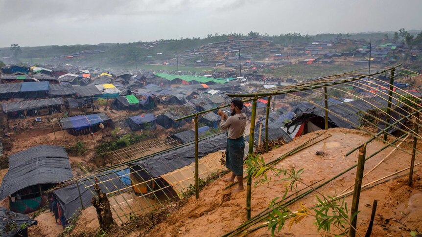 A man builds a shelter overlooking a makeshift camp in Bangladesh.