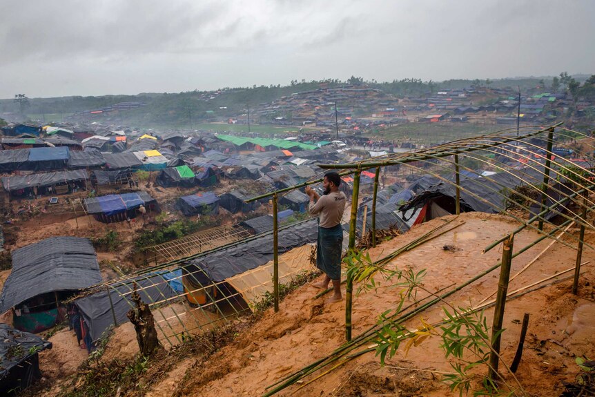 A man builds a shelter overlooking a makeshift camp in Bangladesh.