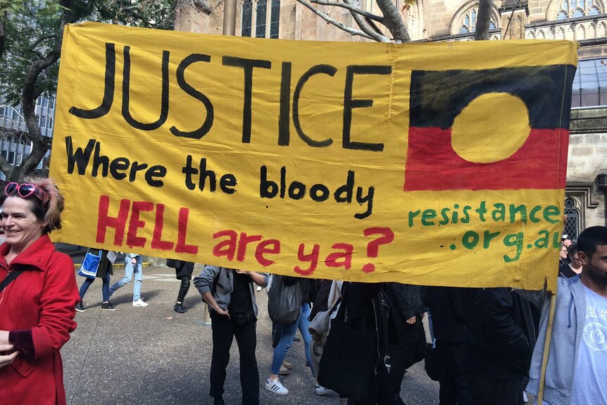 Protesters hold up a placard saying: Justice where the bloody hell are ya?