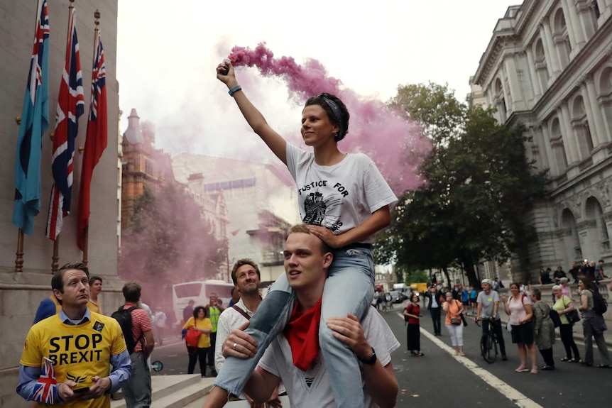 Anti-Brexit supporters carry a flare near the Cenotaph in central London, protesting the plan to suspend Parliament.