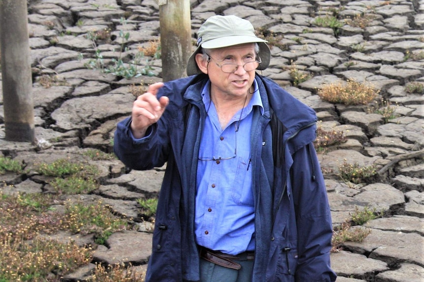 A man talking to someone off camera in a dry lake.