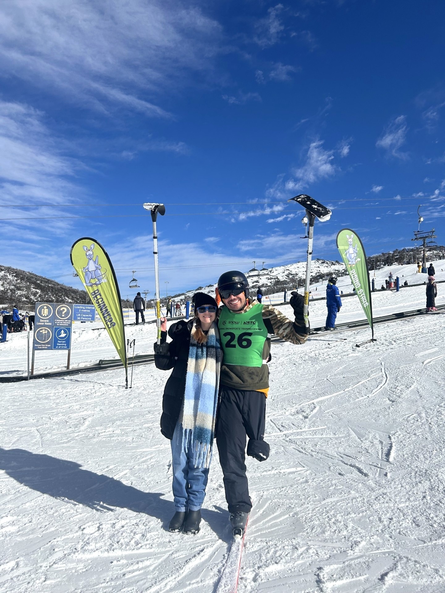 A woman and a one-legged man standing and smiling at the snow