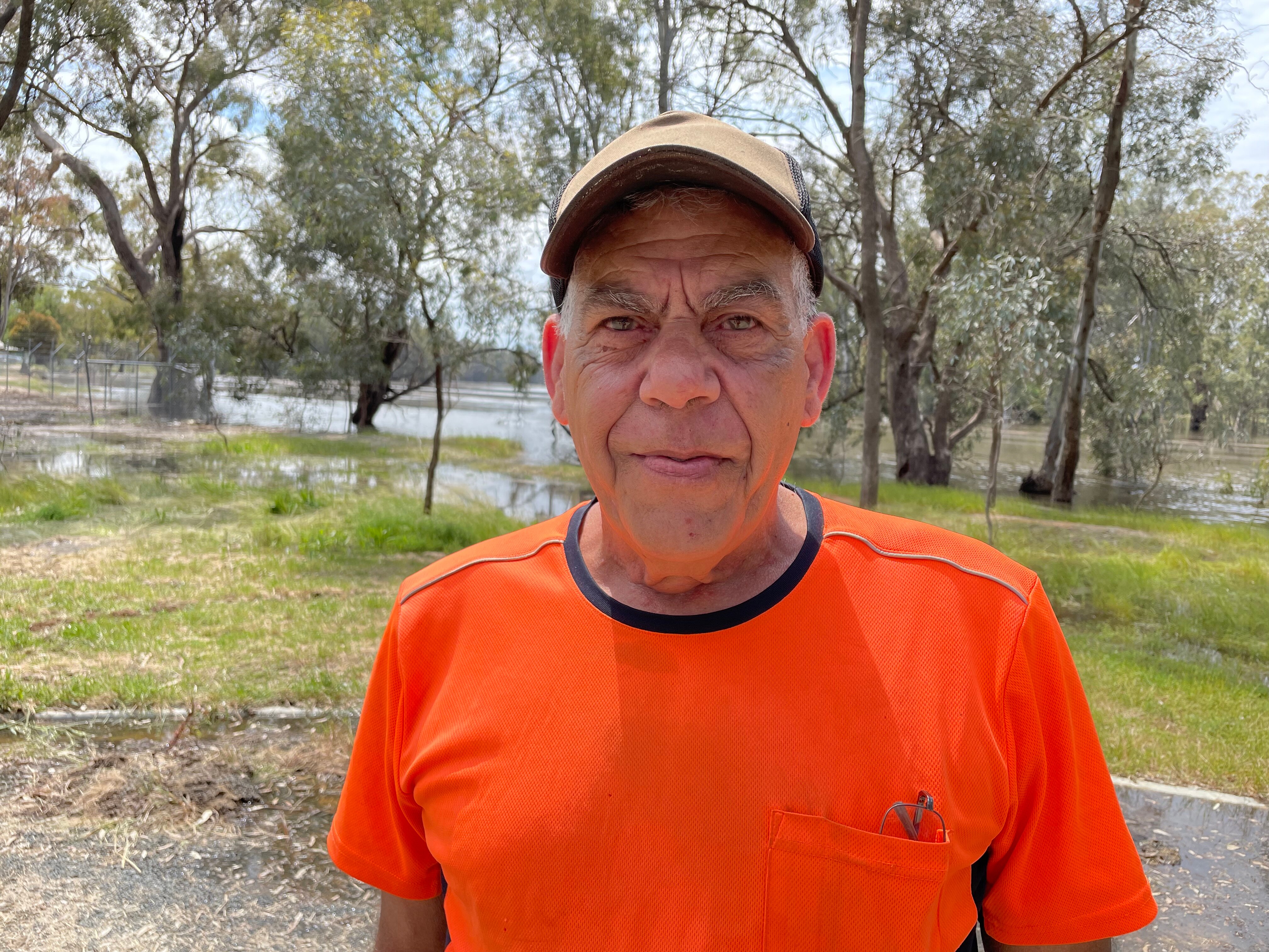 an indigenous man wearing a cap and orange t-shirt.