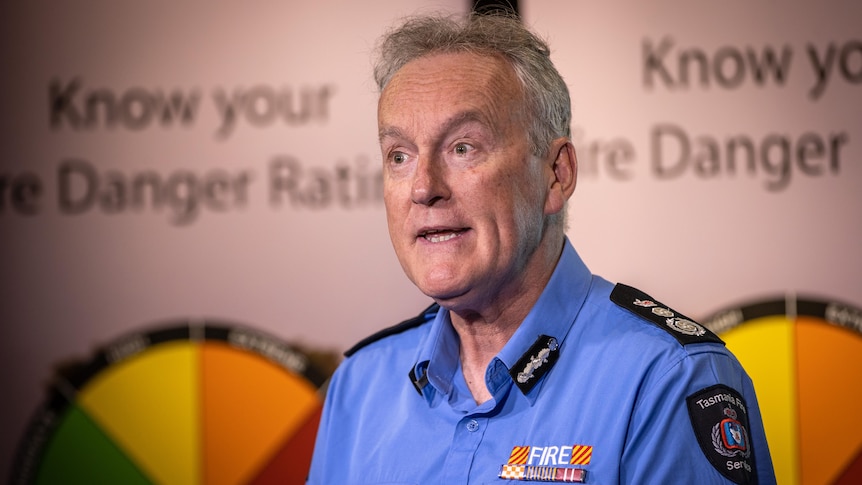 A man wearing a blue uniform speaks at a lectern.