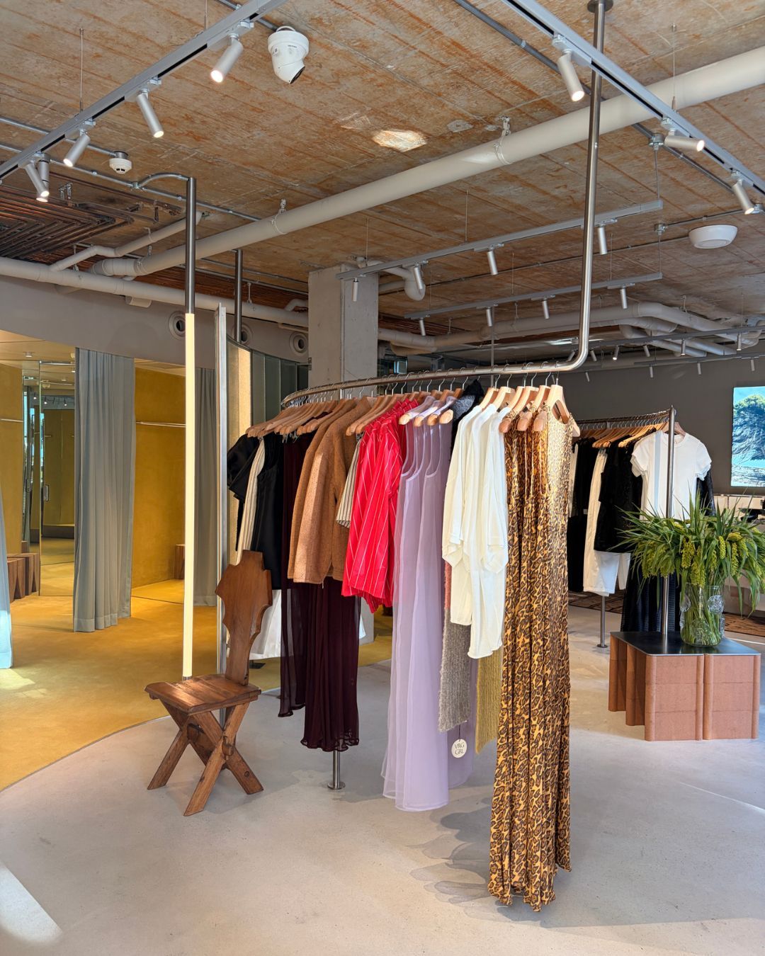 Clothing hanging from a rack suspended from a roof in a store.