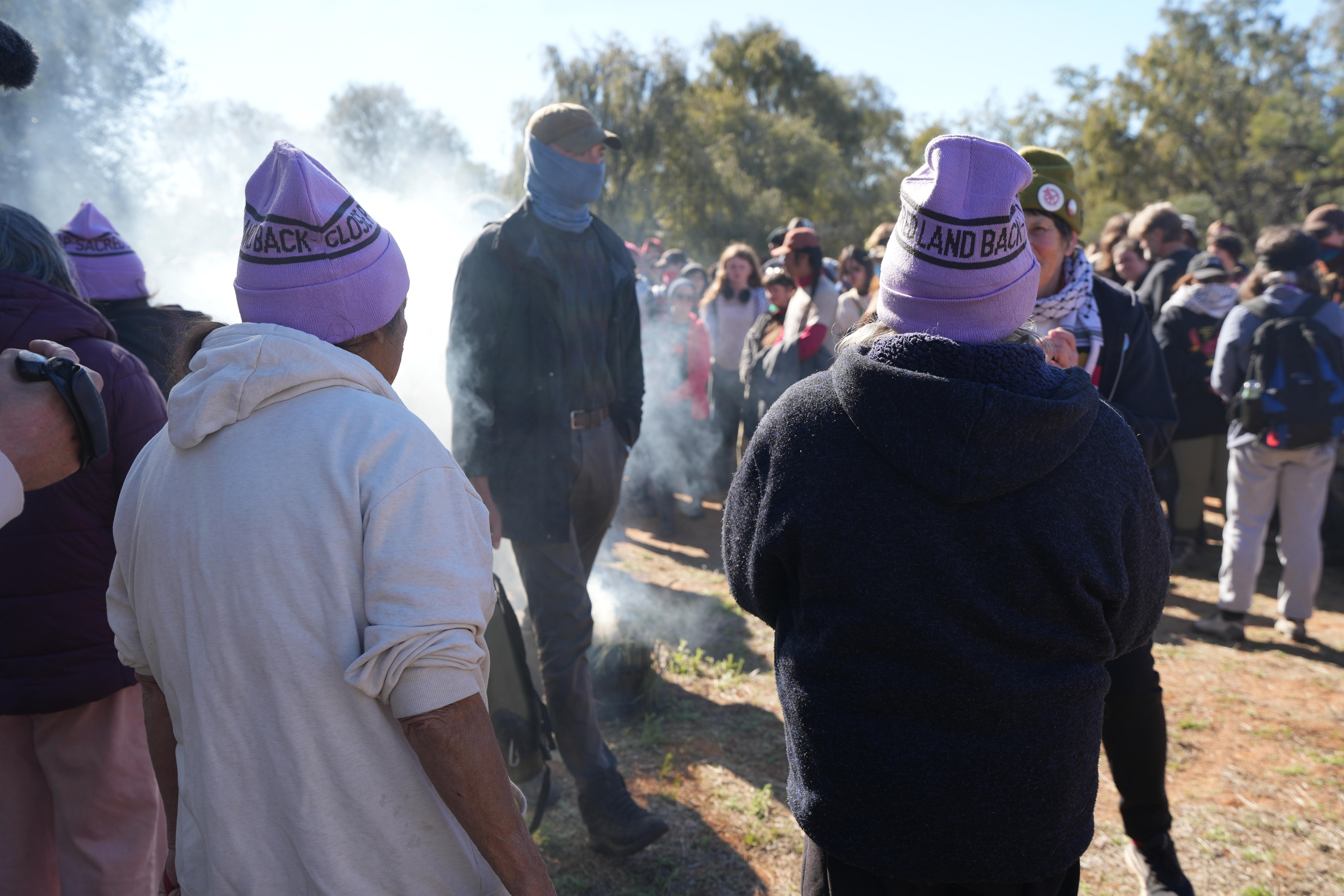 A man walks though smoke in front of two women with their backs to the camera.