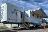 A trailer with the University of Canberra logo sits in a car park, waiting to immunise people