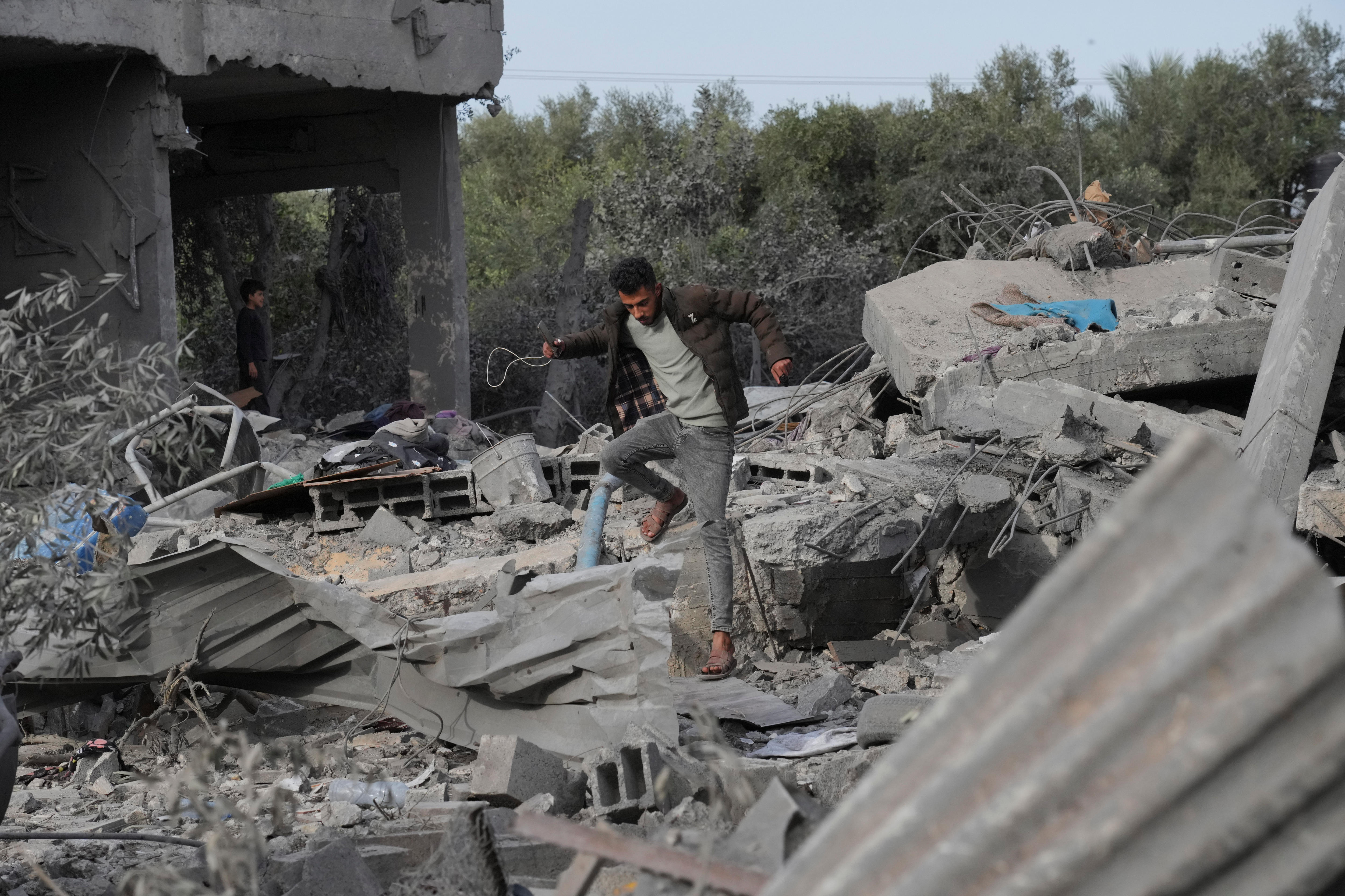 Man walks barefoot on rubble and debris of his home. 