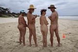 Naked people lined up from  back on the beach