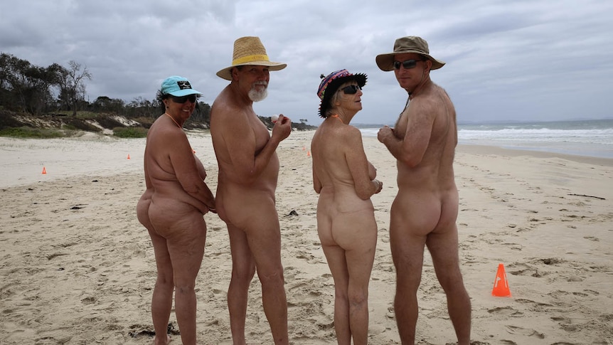 Naked people lined up from  back on the beach