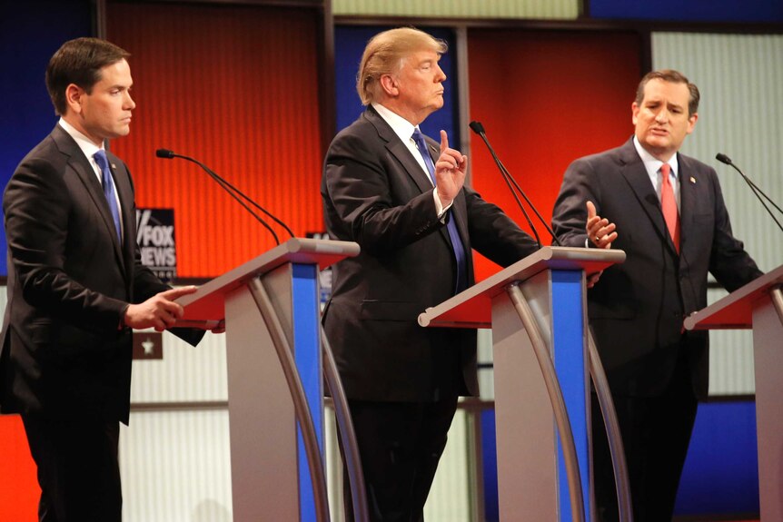 Donald Trump (C) gestures during the Republican debate