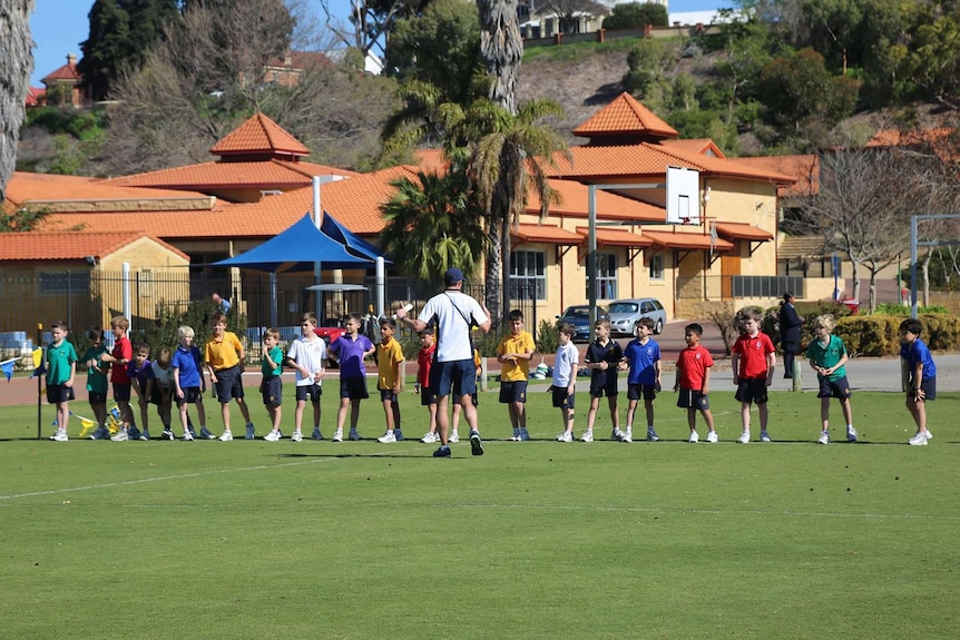 Children line up for running race on an oval at a school cross-country carnival.