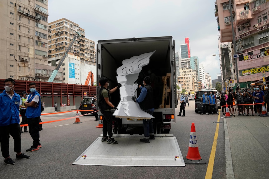 A large cardboard flame is put in the back of a truck by police in a Hong Kong street.