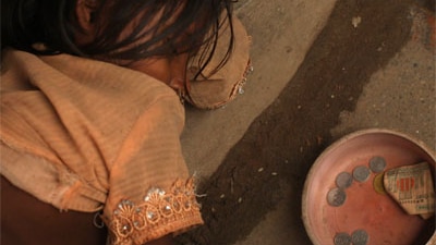 A girl sleeps beside a begging bowl on the ground at a rice market on in Dhaka, Bangladesh, 2008.