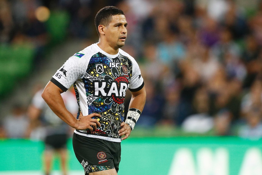 Cody Walker stands with both his hands on his hips wearing an Indigenous jersey