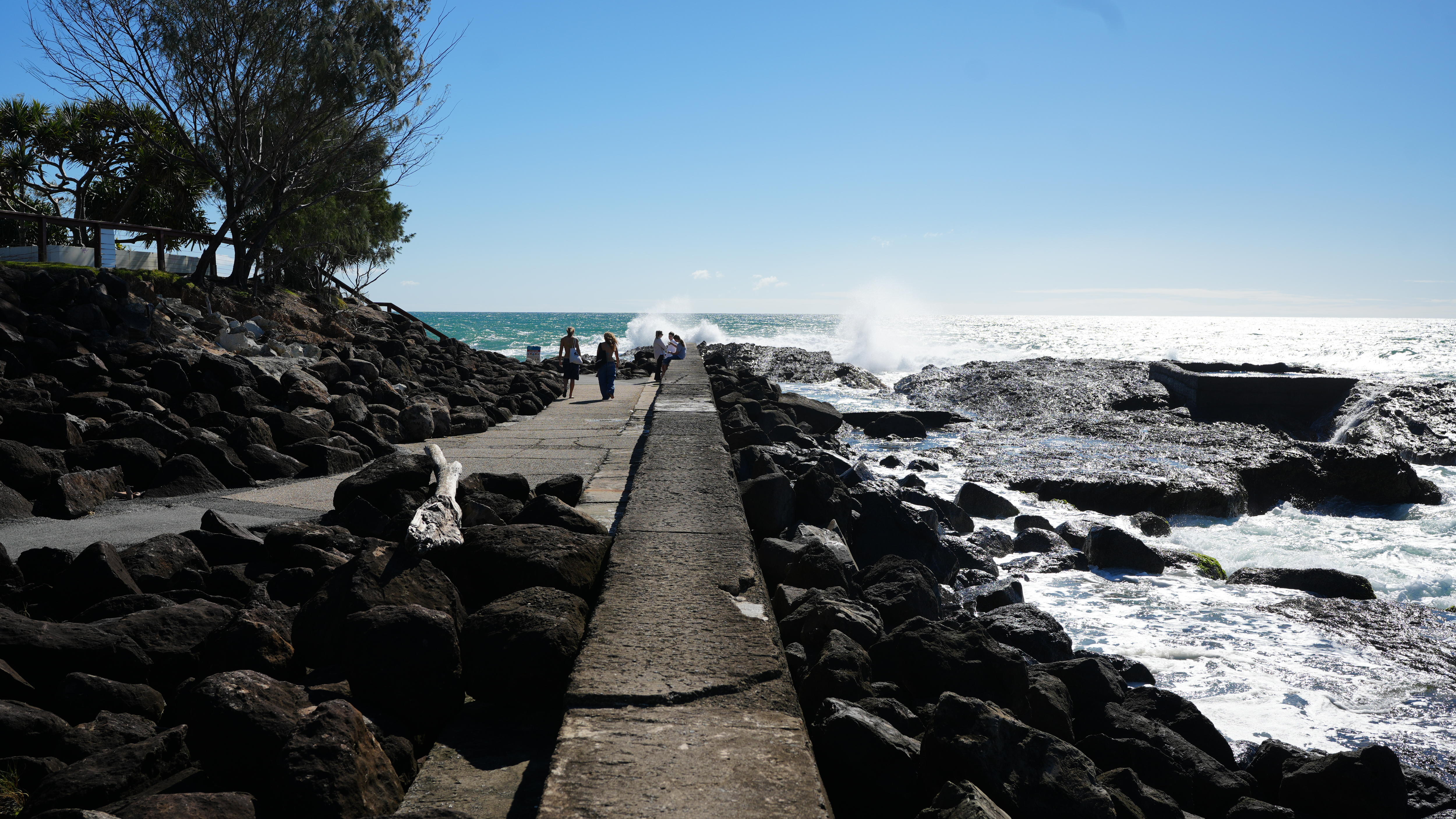 people walking along ocean breakwall