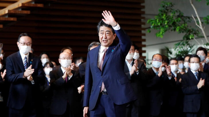 Japan's outgoing Prime Minister Shinzo Abe wave to staff members as they applaud to bid him goodbye at his official residence.