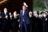 Japan's outgoing Prime Minister Shinzo Abe wave to staff members as they applaud to bid him goodbye at his official residence.