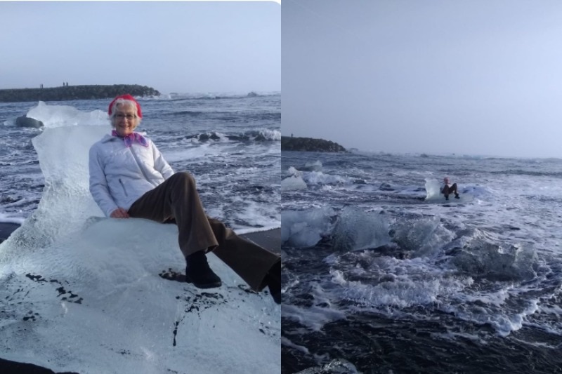 An elderly woman sits on a chunk of ice on the sand of a beach but it soon carried out on the water by a wave.