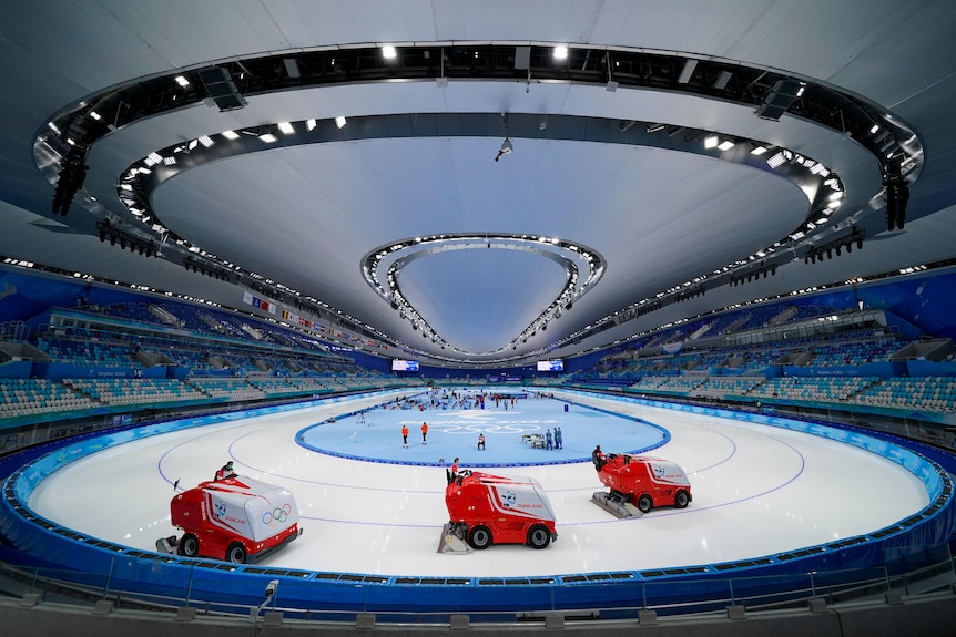 Three Zambonis are seen preparing the ice in an indoor stadium in a fish-eye image