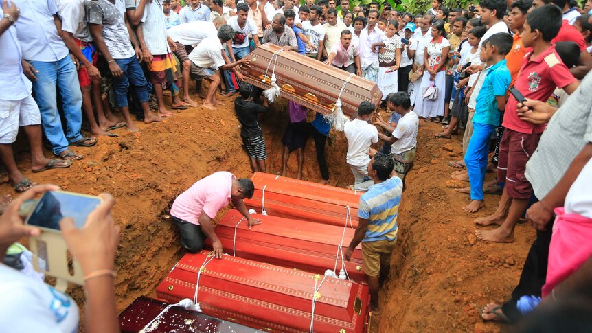 Sri Lankan villagers prepare to bury victims of a landslide at a cemetery.