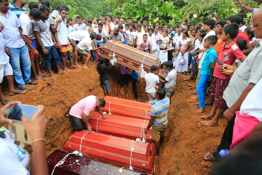 Sri Lankan villagers prepare to bury victims of a landslide at a cemetery.