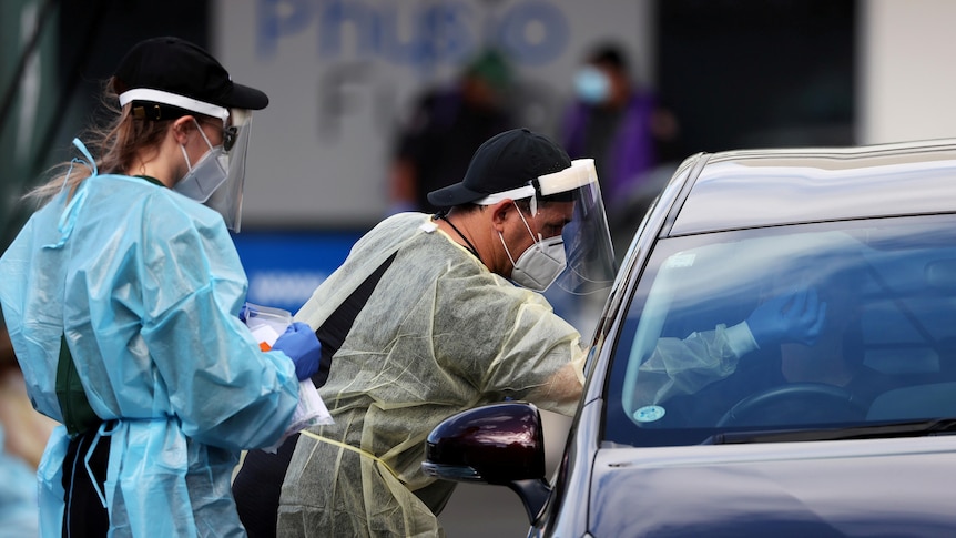 A medical worker administers a COVID-19 test for a driver