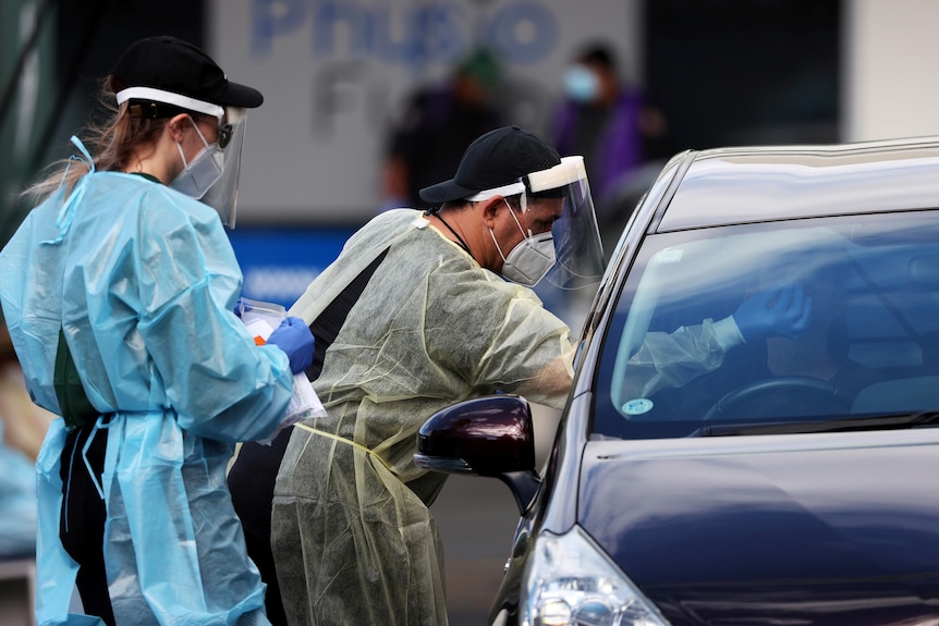 A medical worker administers a COVID-19 test for a driver