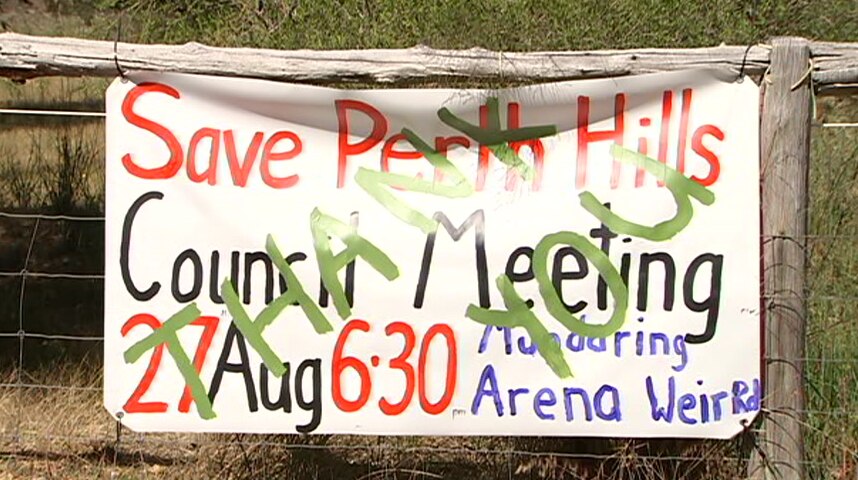 A protest sign hanging on a wooden fence.