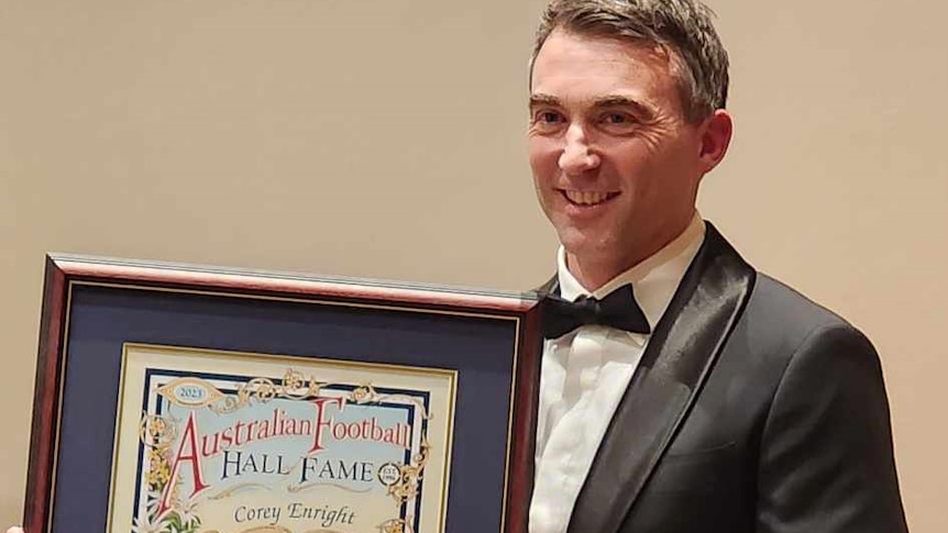 a man in his early 40's stand with an award in a frame