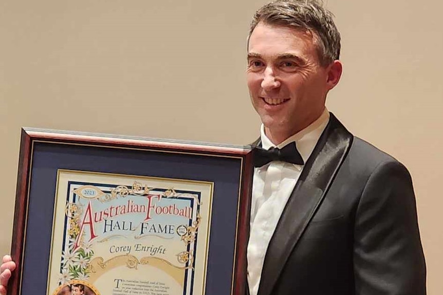 a man in his early 40's stand with an award in a frame
