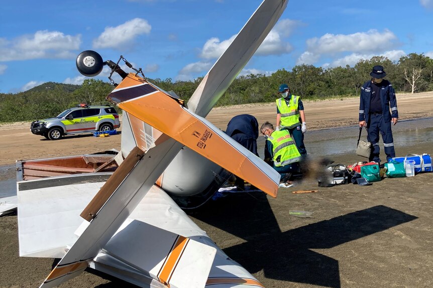 emergency officers kneel beside a crashed plane 