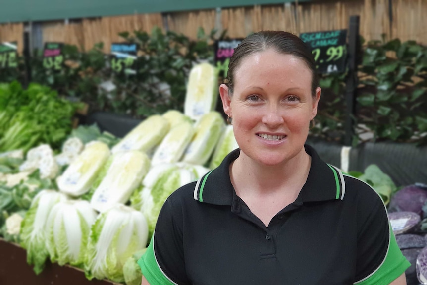 A woman with brown hair standing in front of produce shelves