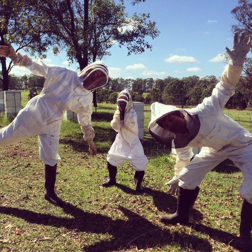 Three people wearing beekeeping suits.