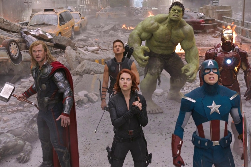 Thor, Hawkeye, Black Widow, The Hulk, Captain America and Iron May stand looking up into the sky surrounded by fire and rubble.